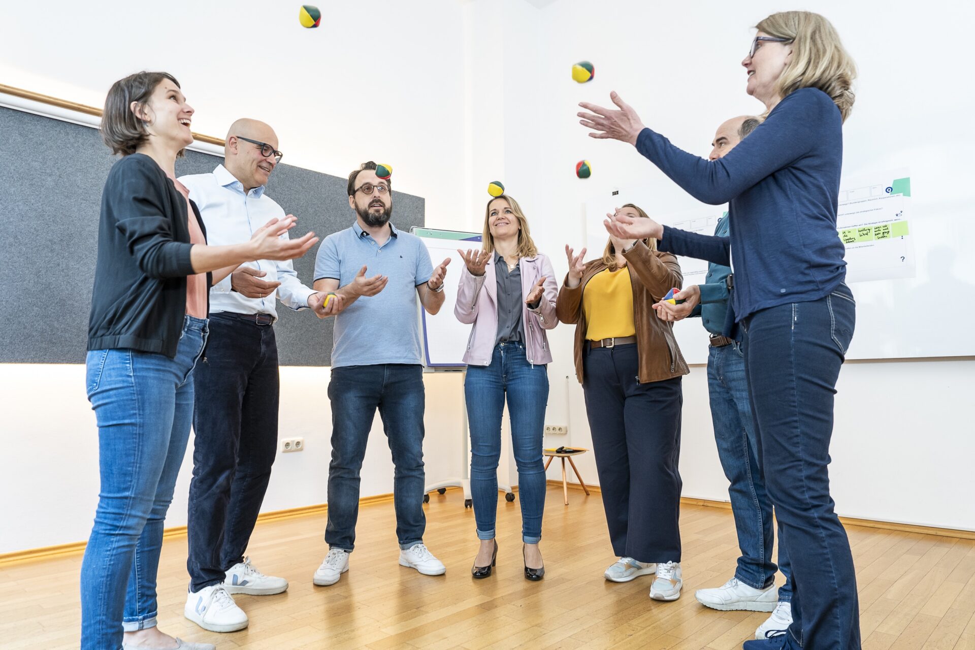 Gruppe jongliert Bälle beim Teamtraining im Seminarraum