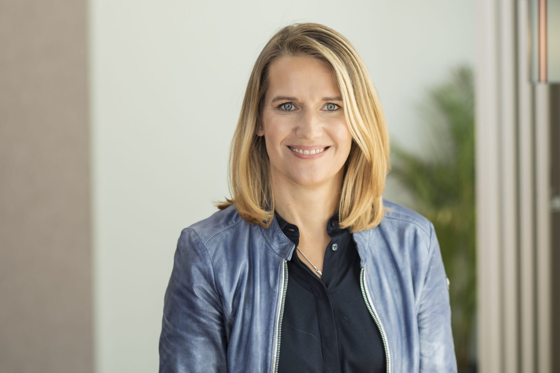 Lächelnde blonde Frau im blauen Lederjacke-Porträt