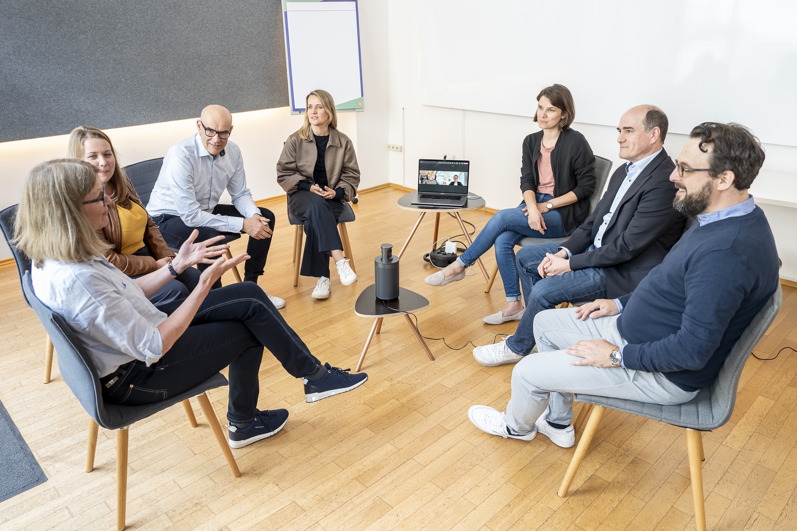 Teammeeting im Stuhlkreis mit Videokonferenz-Laptop