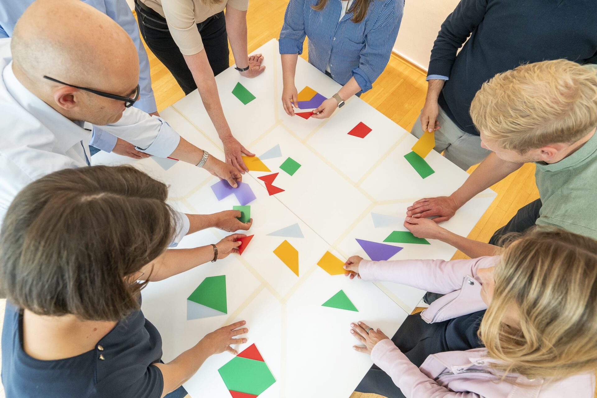 Team ordnet bunte geometrische Formen auf Tisch