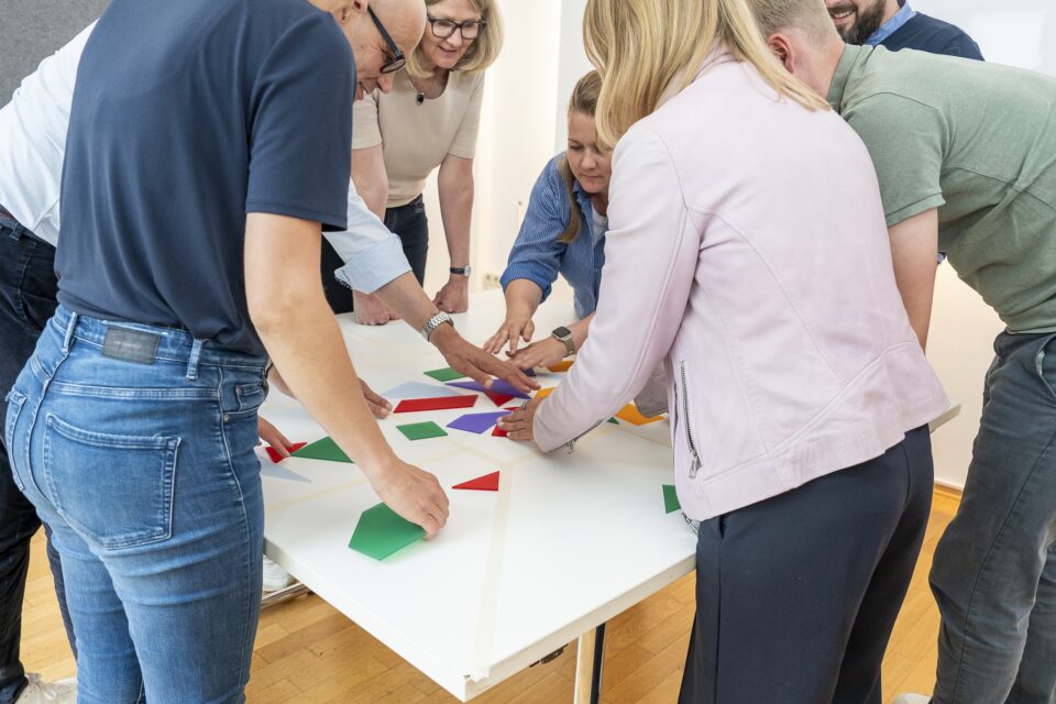 Team arbeitet gemeinsam mit bunten Formen am Tisch