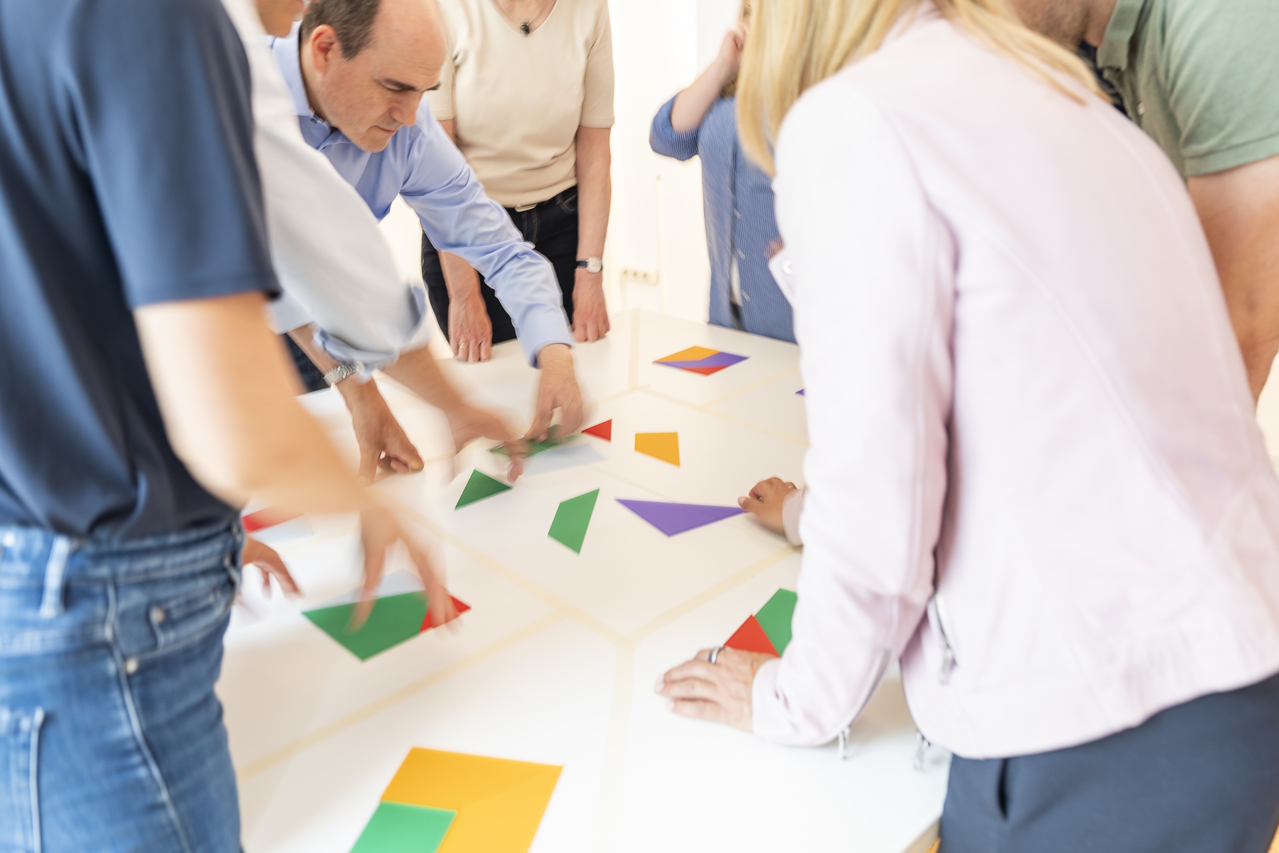 Team ordnet bunte geometrische Formen auf Tisch
