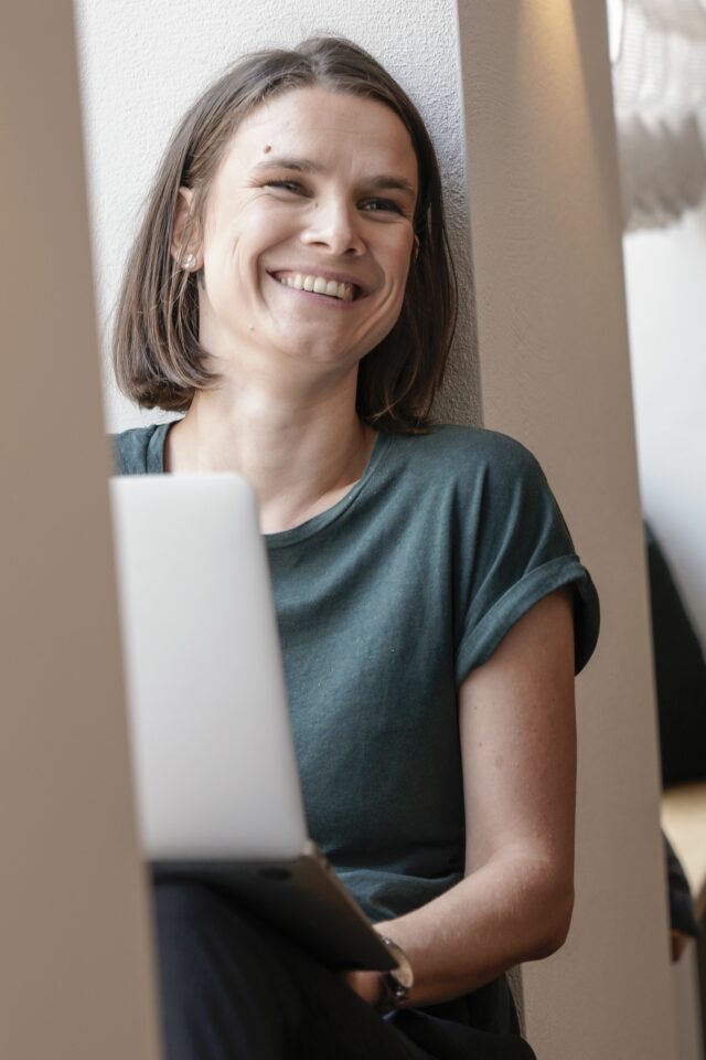 Lächelnde Frau mit Laptop im Innenraum