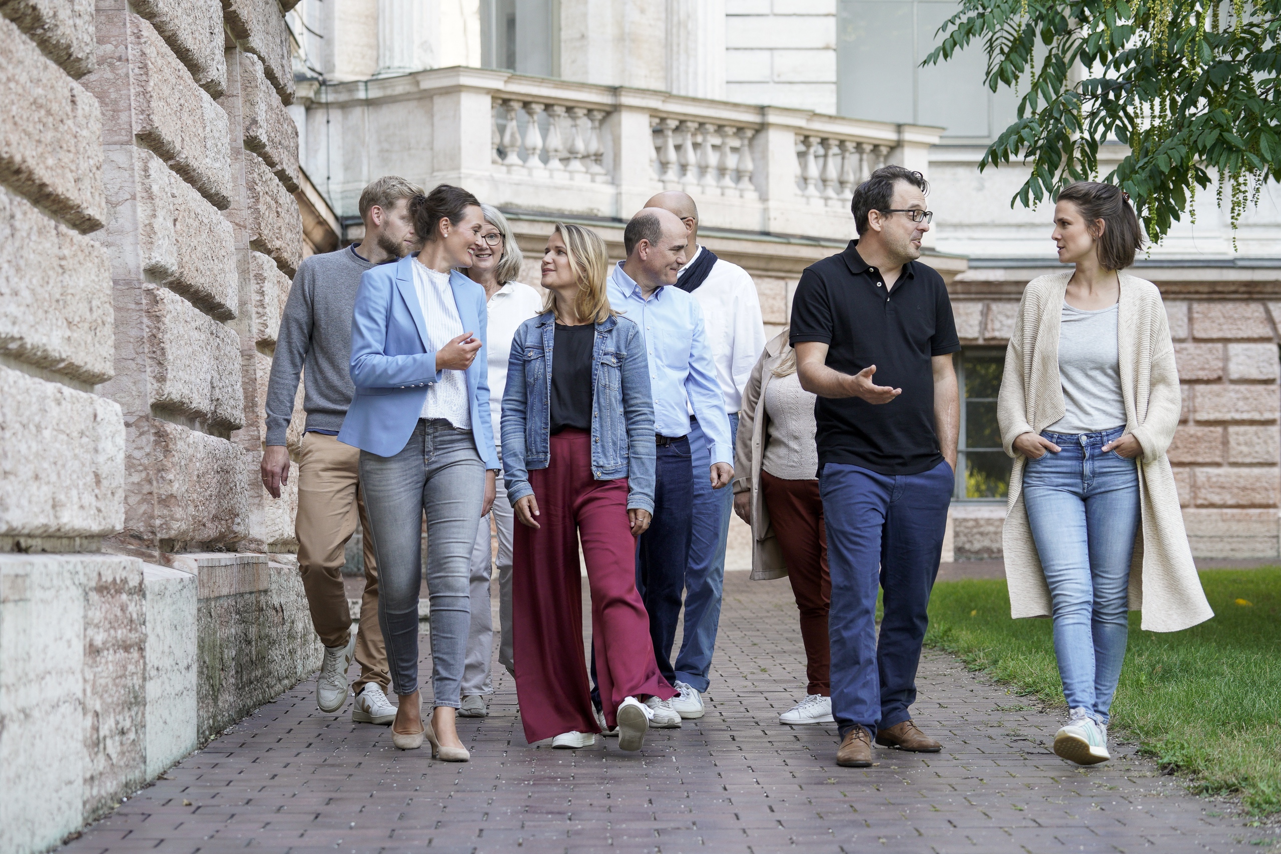 Gruppe Erwachsener im Gespräch vor historischem Gebäude