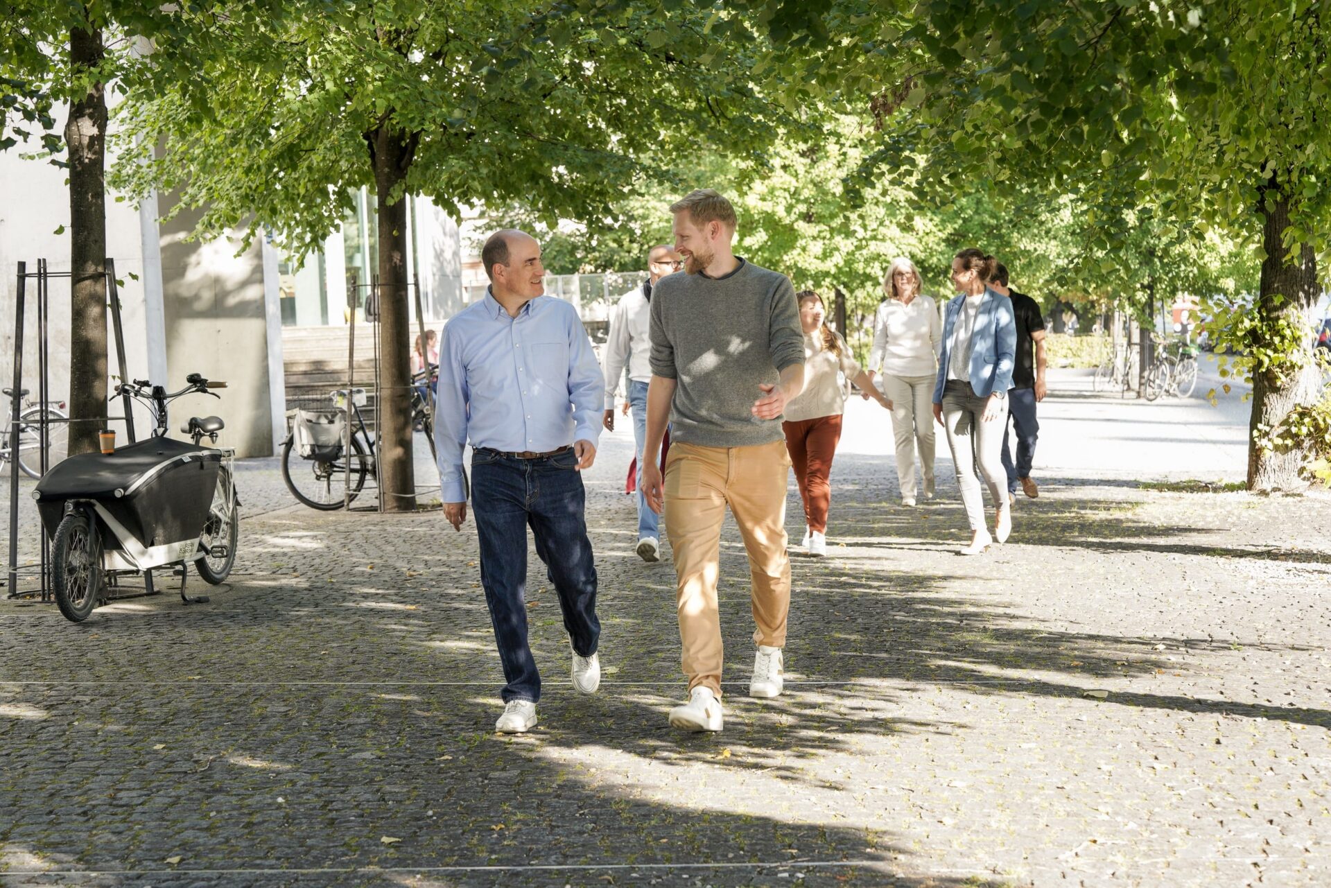 Gruppe spaziert auf sonniger, baumgesäumter Straße