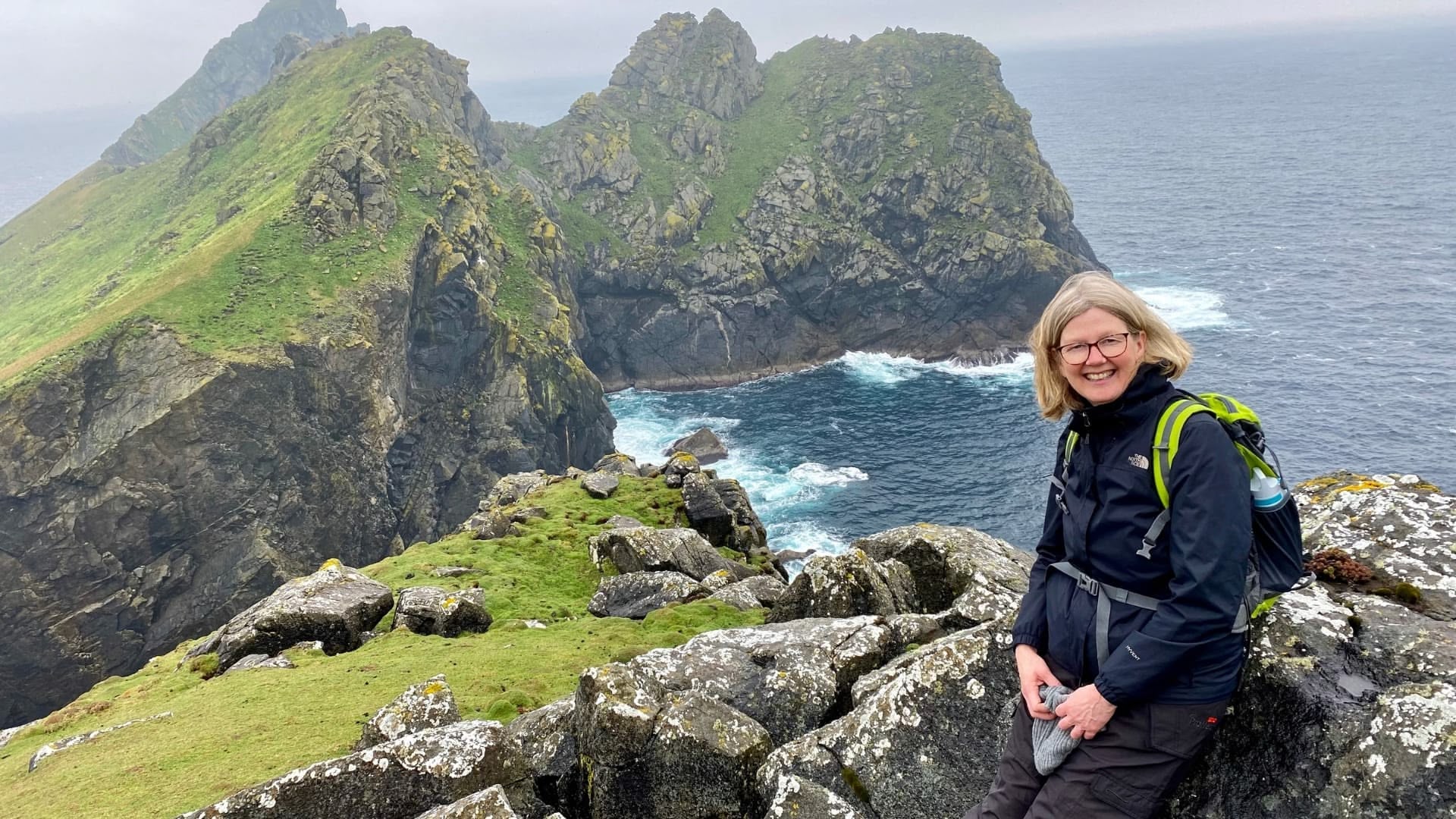 Frau auf Klippen mit grünem Küstenpanorama