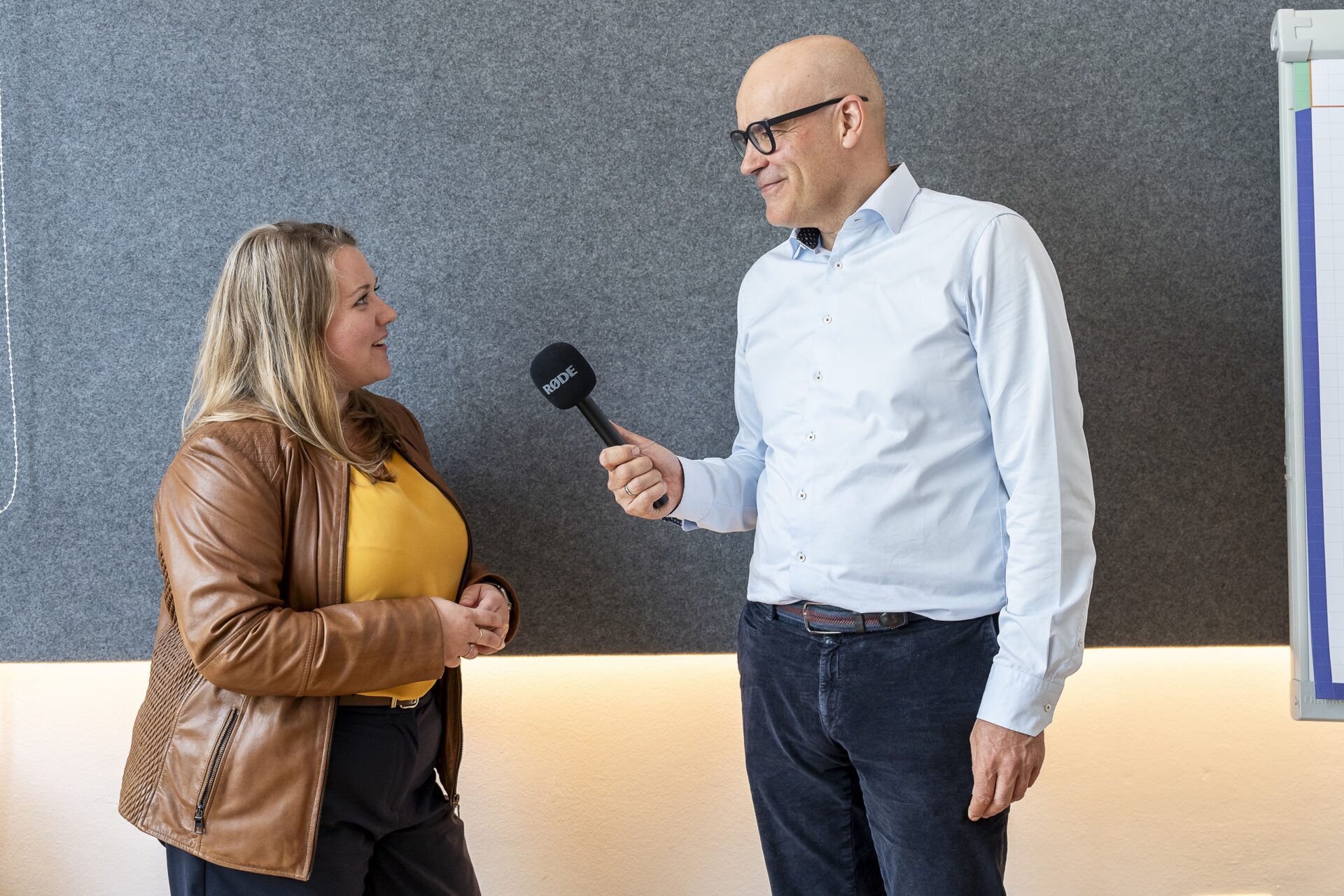 Mann interviewt Frau mit Mikrofon im Büro