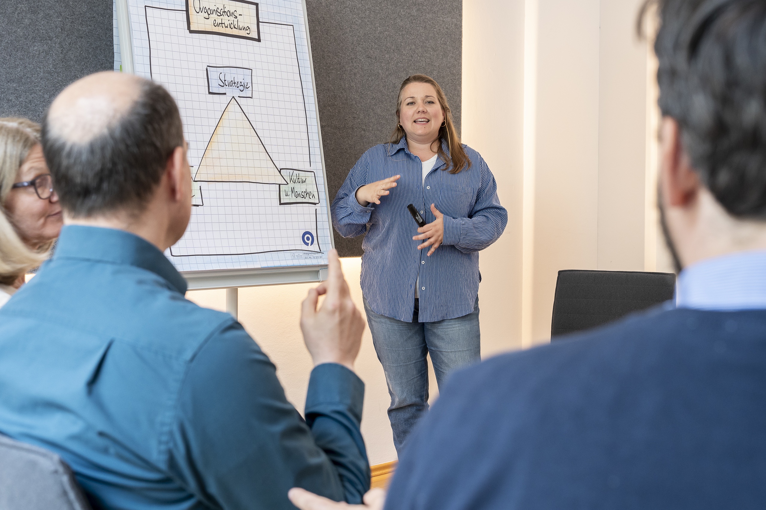 Frau hält Präsentation vor Team im Besprechungsraum