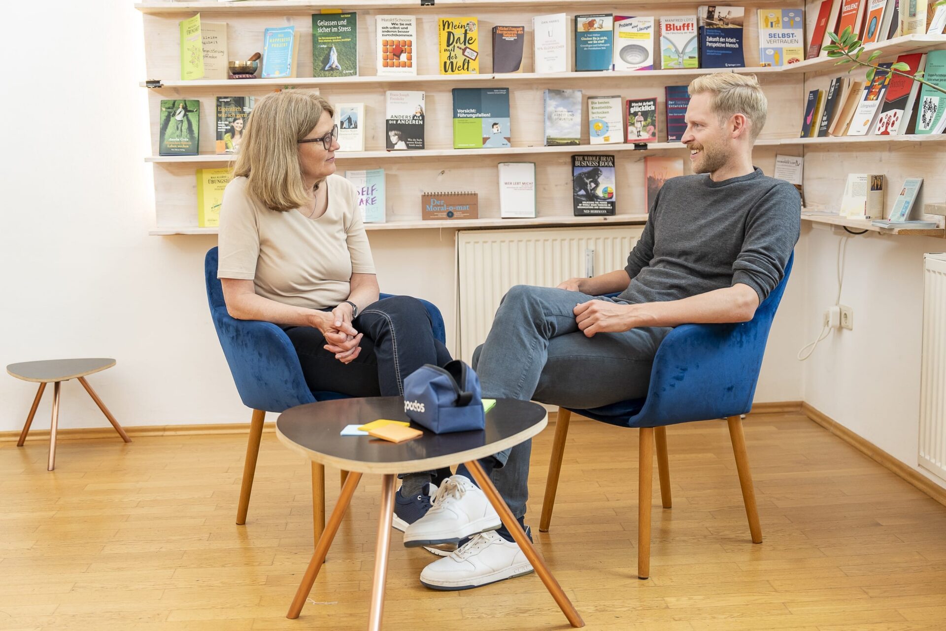 Zwei Personen im Gespräch vor Bücherregal im Büro
