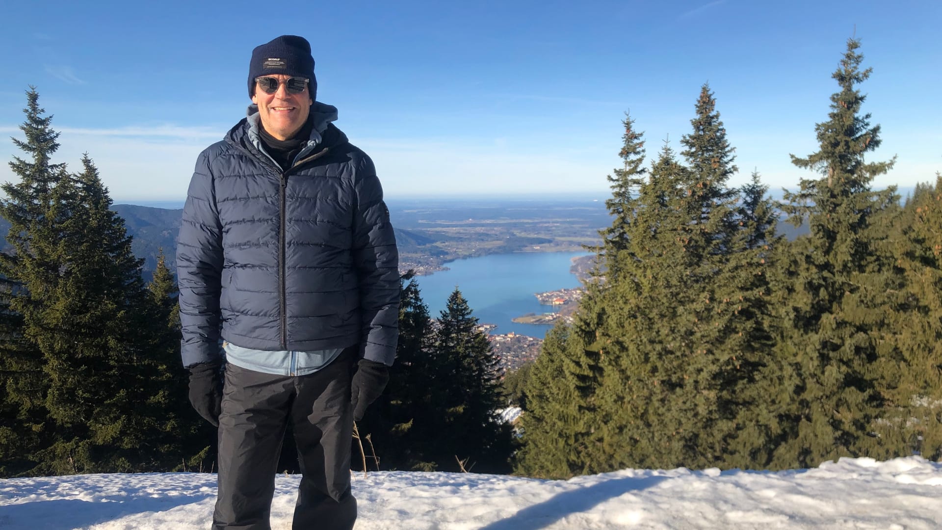 Mann auf verschneitem Berg mit Seeblick